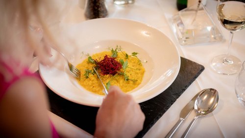 Tobogganing in Tyrol – fun for the whole family Person eating saffron risotto with herbs on a white plate