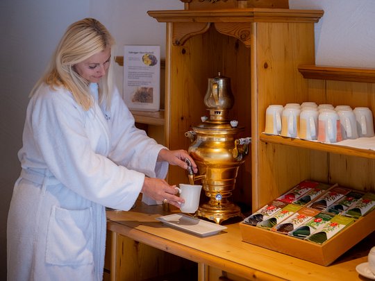 Accommodation in St. Jakob in Defereggental: healing water Woman in bathrobe pouring tea from a traditional samovar