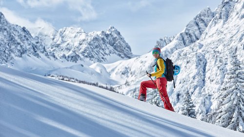 Tobogganing in Tyrol – fun for the whole family Hiker in colorful clothes in a snowy mountain landscape