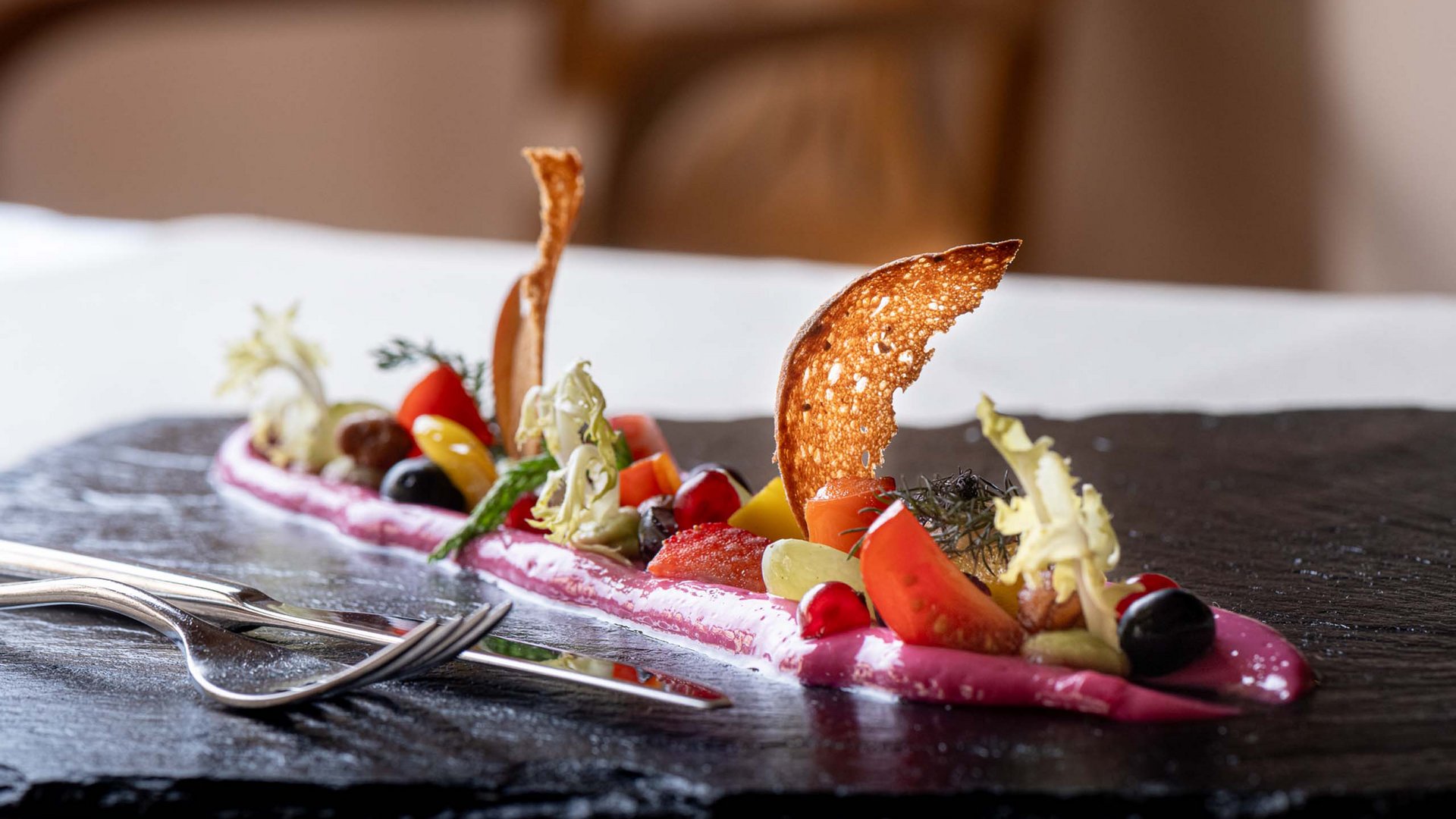 Jesacherhof: Ihr Hotel im Defereggental Fein angerichtete Gourmet-Vorspeise mit frischen Zutaten und knusprigem Brot auf schwarzem Stein