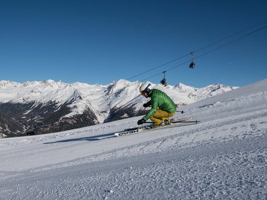 Jesacherhof: Ihr Hotel im Defereggental Skifahrer in grüner Jacke und gelber Hose beim Kurvenfahren auf verschneiter Piste
