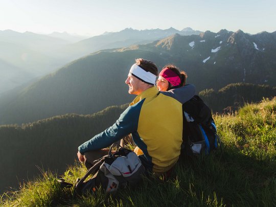 Jesacherhof: Ihr Hotel im Defereggental Paar sitzt auf grasigem Berggrat und genießt die Aussicht bei Sonnenuntergang